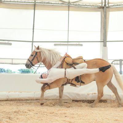 Voltigeuse en figure allongée sur un cheval palomino